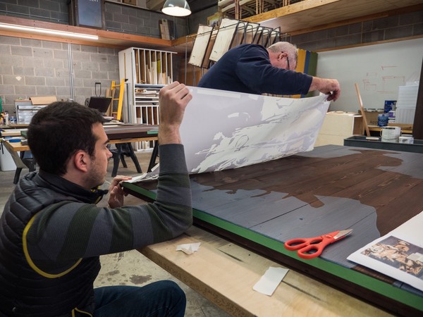 two people apply cut vinyl stencils to a panel