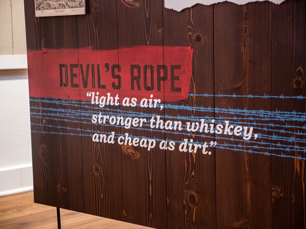 stenciled barbed wire overlaid with 'devil's rope: light as air, stronger than whiskey, and cheap as dirt'