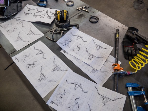 printout plans for the heads of longhorn sculptures amid clamps, gloves, and ear protection