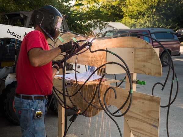 sparks rain down while welding pieces of a longhorn sculpture