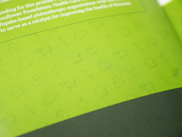 detail of green booklet cover showing simple graphic pattern of bread, milk carton, apple, cow, carrot, and watermelon
