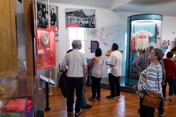 Many people view the exhibits. Artifacts and photos from internment camps are on display along with a map of camp locations.