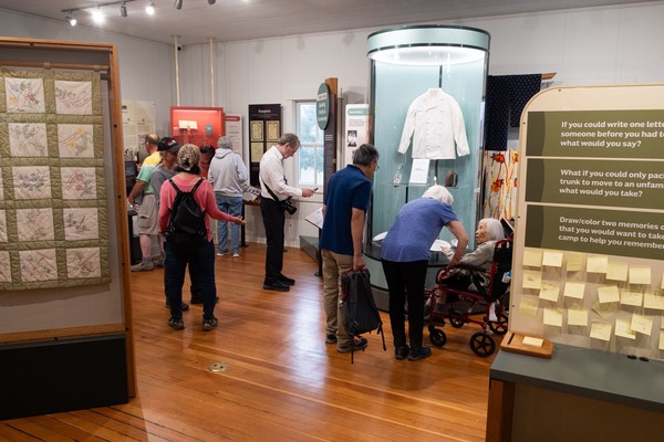 An especially elderly woman talks with another woman in front of a display case featuring a chef's jacket from the Eagle Cafe.