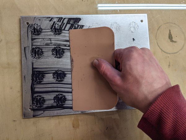 Spreading enamel on the engraved aluminum with a squeegee