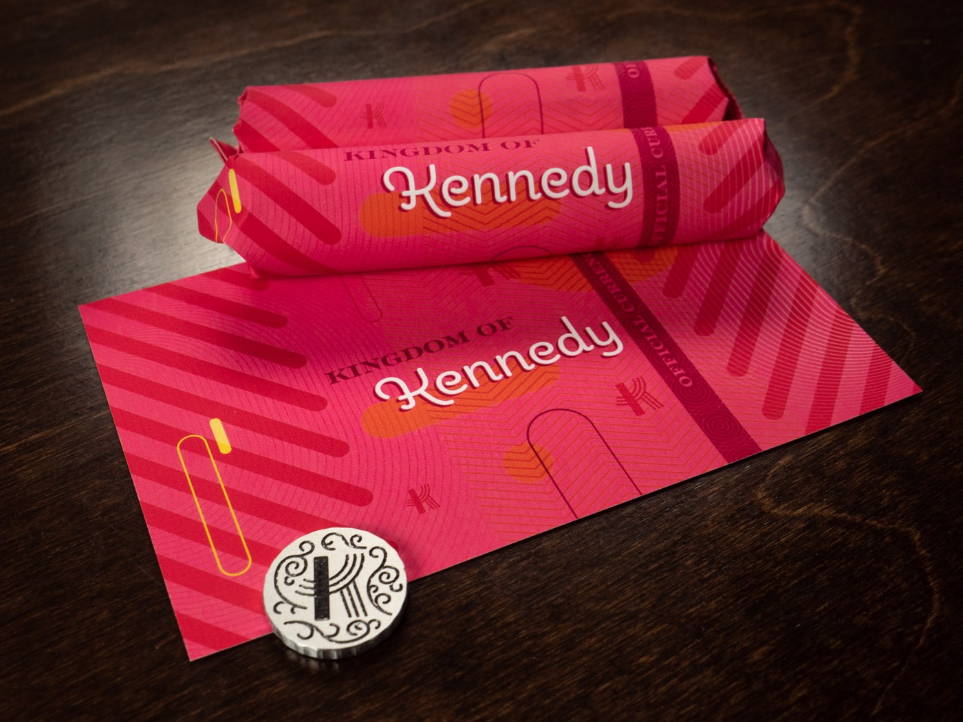 rolls of coins in bold pink and magenta sleeves with text reading 'Kingdom of Kennedy' and 'Official Currency'