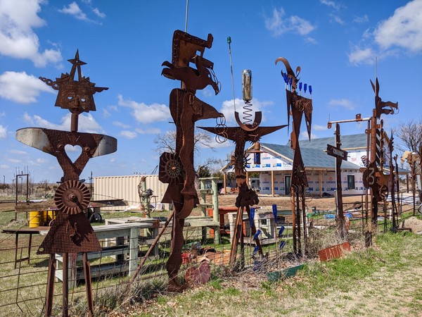 Abstract metal figures in a fenceline in front of under-construction visitors center