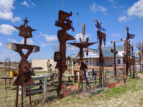 Abstract metal figures in a fence line in front of under-construction visitors center