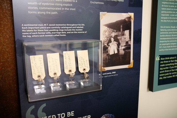 four wedding rings in a display case with handwritten tags of information about each wife