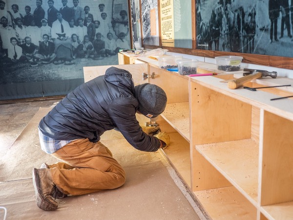 carpenter adjusts hinge hardware inside cabinet