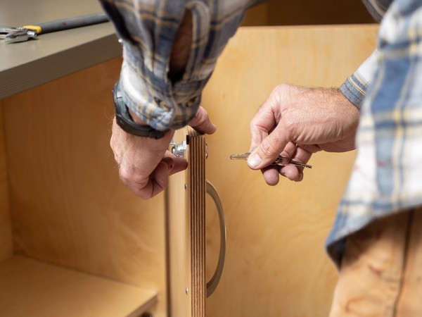 carpenter inserts key into cabinet door lock