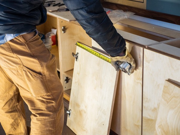 carpenter measures unattached cabinet door