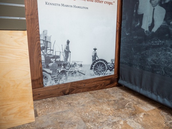 lower portion of interpretive panel showing historic photo of men driving farm equipment